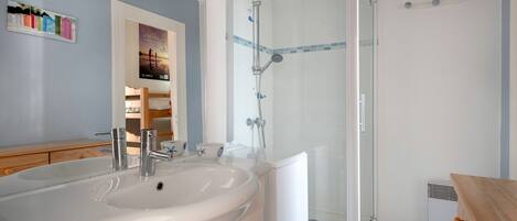 A bathroom with a white sink, a shower with a glass door, and a wooden vanity.