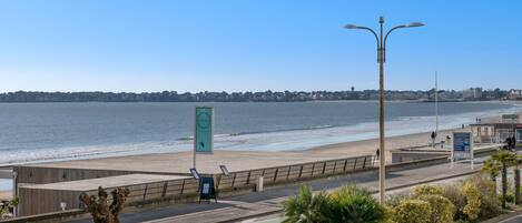 A coastal promenade with a view of the sea, a pedestrian path, and a street with a bike lane.