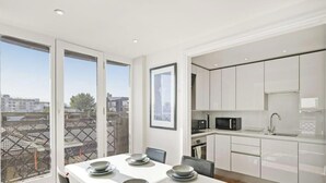 A modern kitchen with white cabinets, a microwave, and a sink.
