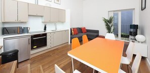 A modern kitchen with a dining area, a sofa, and a window with a view.