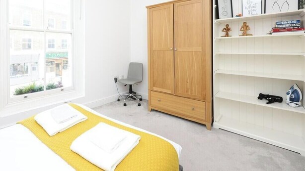 Une chambre à coucher comprenant un lit, une chaise, une armoire et une étagère avec des objets.