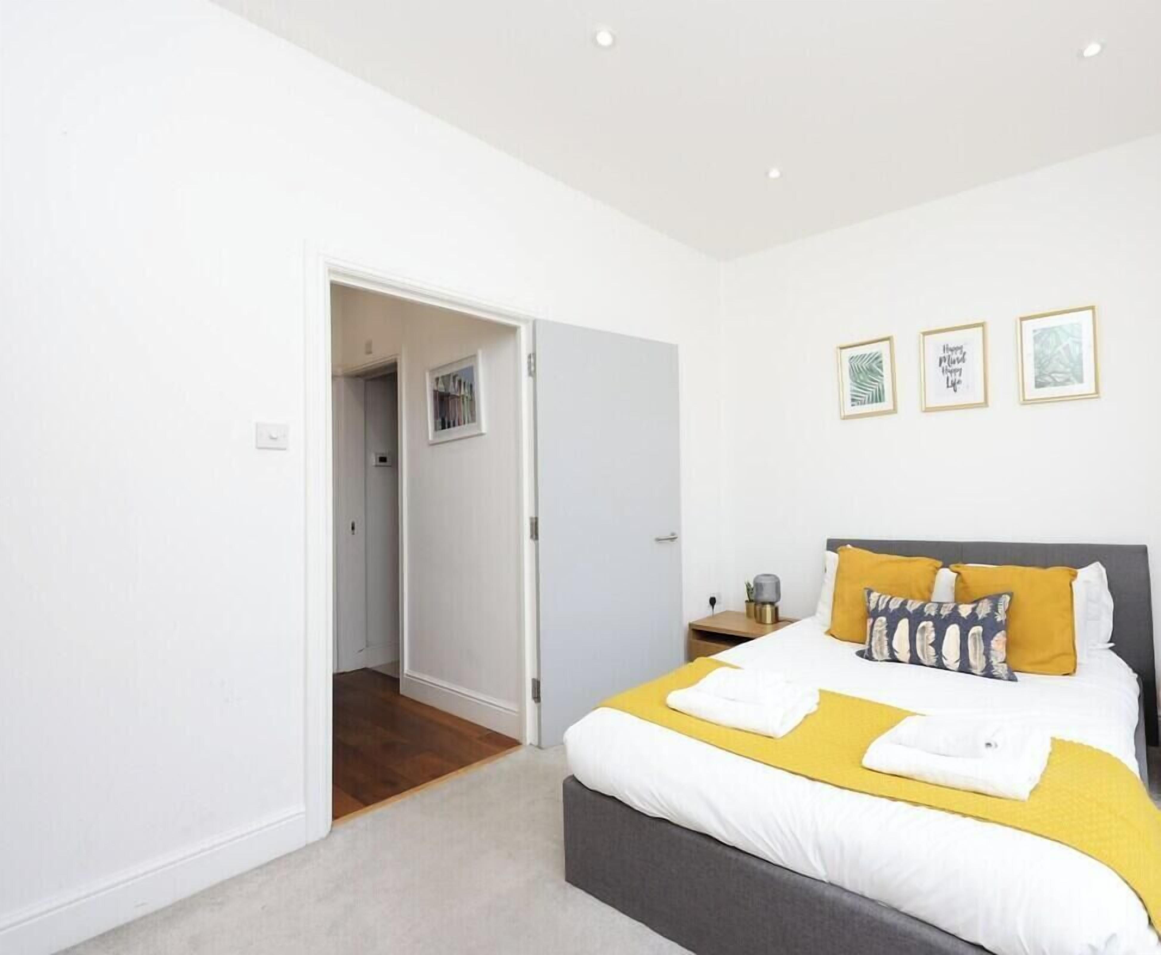 Een slaapkamer met een bed, nachtkastje en een deur naar een andere kamer.