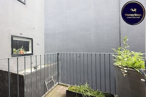 A balcony with a metal railing, a potted plant, and a sign for Murray Stays.