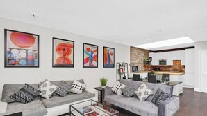 Un salon moderne avec un canapé, une table basse et des œuvres d’art accrochées au mur.