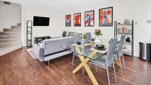 Un salon moderne avec un canapé, une table à manger, des chaises et des œuvres d’art accrochées aux murs.
