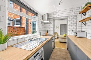 A compact kitchen with a window, built-in dishwasher, and a small dining area with a sofa.