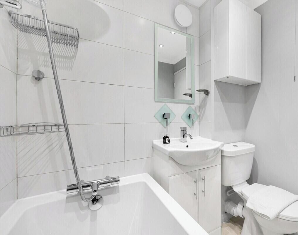 Uma casa de banho moderna com banheira, lavatório, sanita e chuveiro.