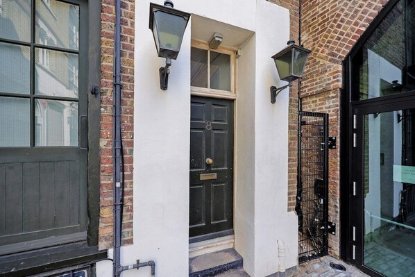 A building with a black door, a white wall, and a brick facade.