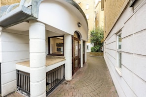 A narrow alleyway with a white building on the left and a beige building on the right.