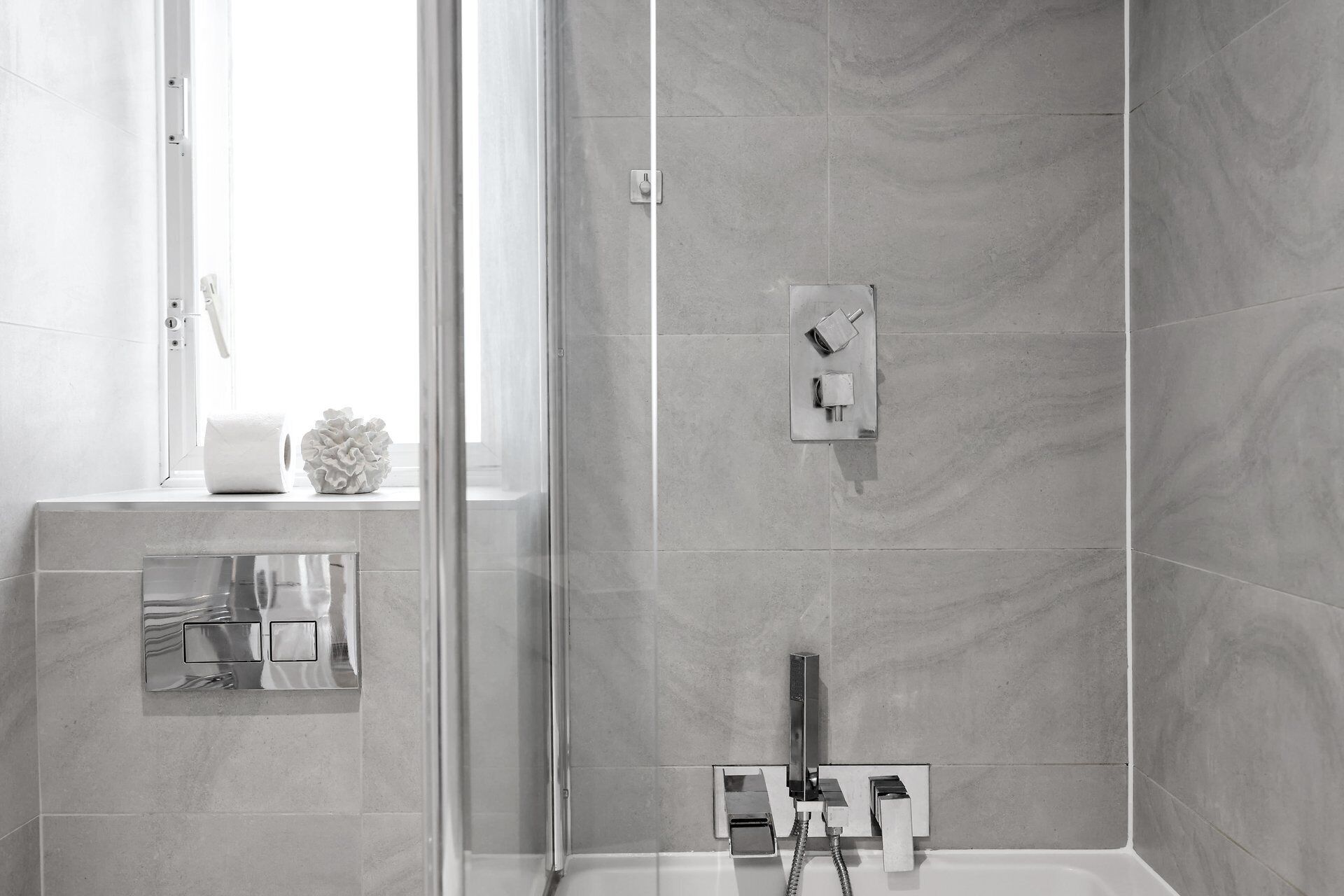 Ein modernes Badezimmer mit Dusche, Toilette und Fenster.