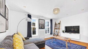 A modern living room with a sofa, a coffee table, a TV, and a bookshelf.
