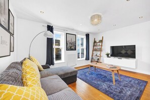A modern living room with a sofa, a coffee table, a TV, and a bookshelf.