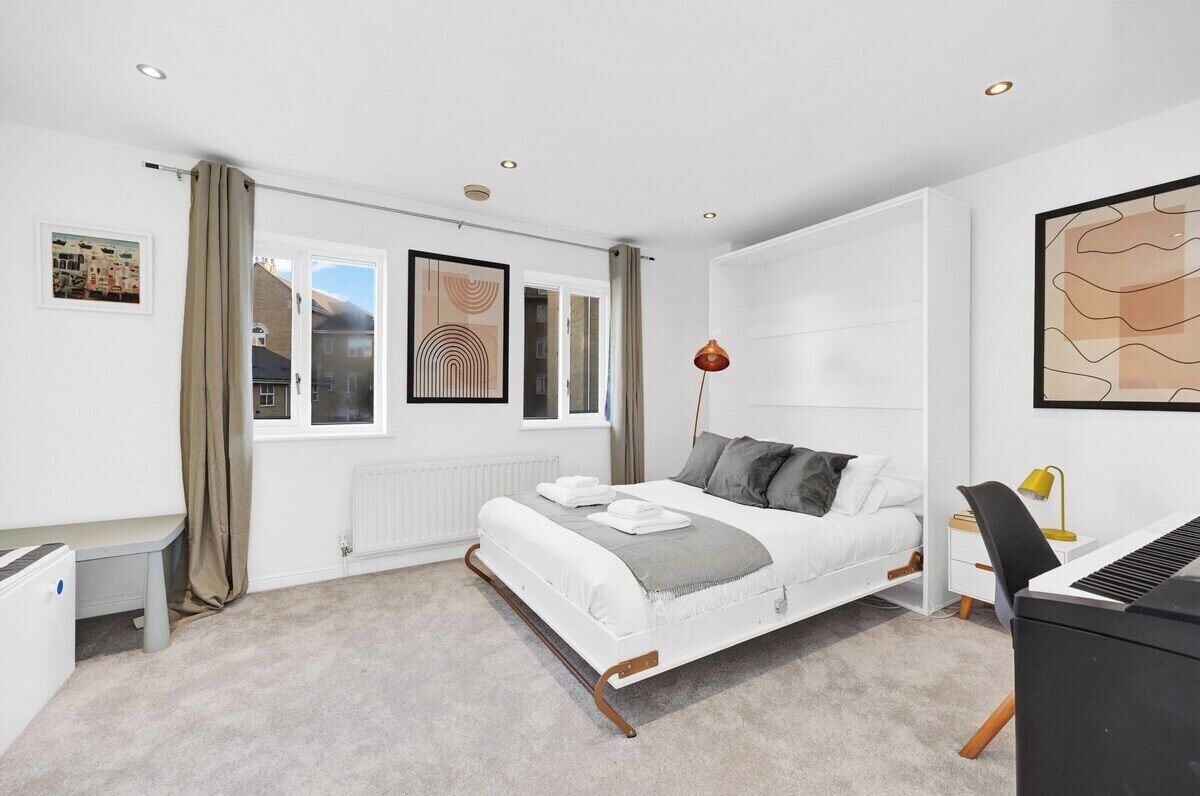 Ein modernes Schlafzimmer mit einem Bett, einem Schreibtisch, einem Stuhl und einer Heizung.