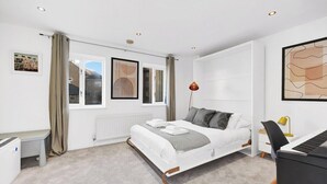 A modern bedroom with a bed, a desk, a chair, and a radiator.