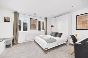 A modern bedroom with a bed, a desk, a chair, and a radiator.