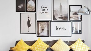 A wall with framed pictures and a sofa with patterned cushions.