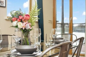 A dining table set with plates, bowls, and wine glasses, with a vase of flowers in the center.