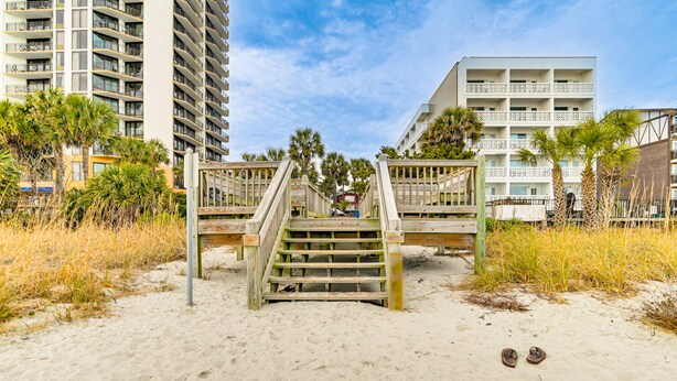 A wooden staircase leading to a beach area with sandy ground and a pair of sandals on the sand. - 1 Mi to Boardwalk & Dtwn: Myrtle Beach Condo (Myrtle Beach)