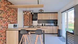 Een moderne keuken met een bakstenen muur, houten kasten, een groot eiland met krukken en uitzicht door een schuifdeur.