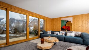En moderne stue med store skydedøre af glas, en blå sofa og et træbord.