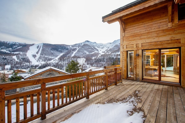A wooden cabin with a balcony overlooking a snowy mountain landscape.