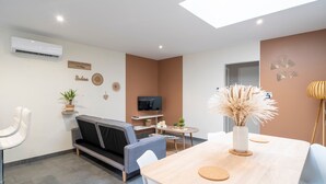 Ein modernes Wohnzimmer mit Sofa, Esstisch, Fernseher und Dekorationselementen.