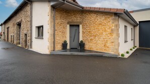 Ein Gebäude mit einer Steinfassade, einer grauen Tür, Pflanzkübeln und einem gepflasterten Eingang.