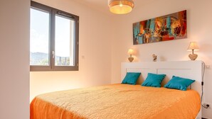 A bedroom with a large bed, two bedside lamps, a painting, and a window. - Stella di Luce - Appt climatisé vue mer (Lumio)