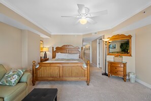 Quarto com cama de madeira, ventoinha no teto, cômoda, espelho e poltrona verde.