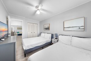 A modern bedroom with two beds, a ceiling fan, a TV, and artwork on the walls. - Stone Harbour 304 by Seaside Vacations & Sales (Ocean city)