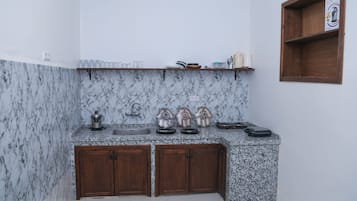 Una cocina con salpicadero de mármol, armarios de madera y una estantería con utensilios de cocina.