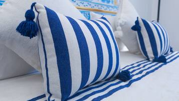 A bed with white and blue striped bedding and blue tassels.