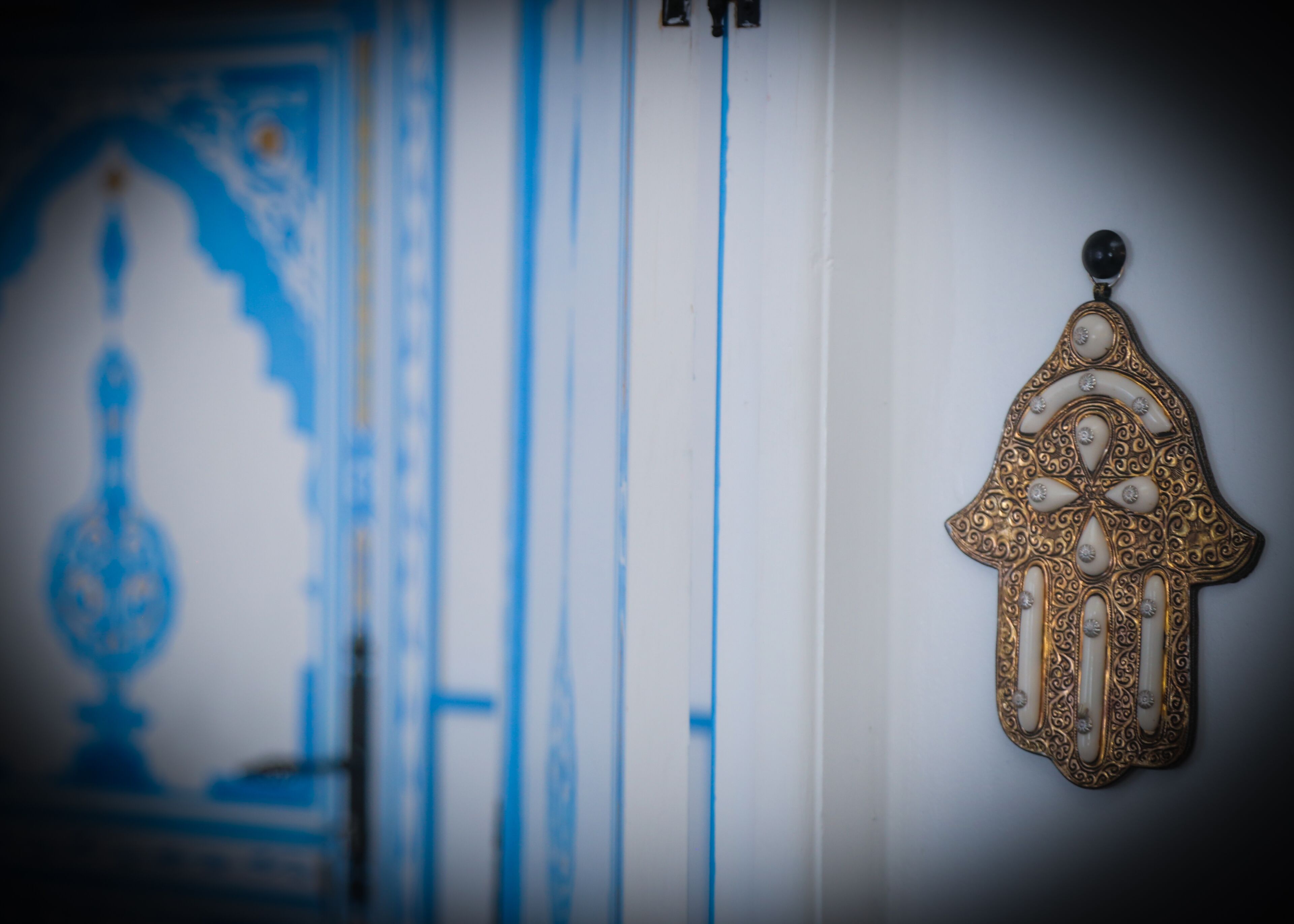 A room with a blue and white patterned wall, a decorative hanging ornament, and a vertical blue stripe.