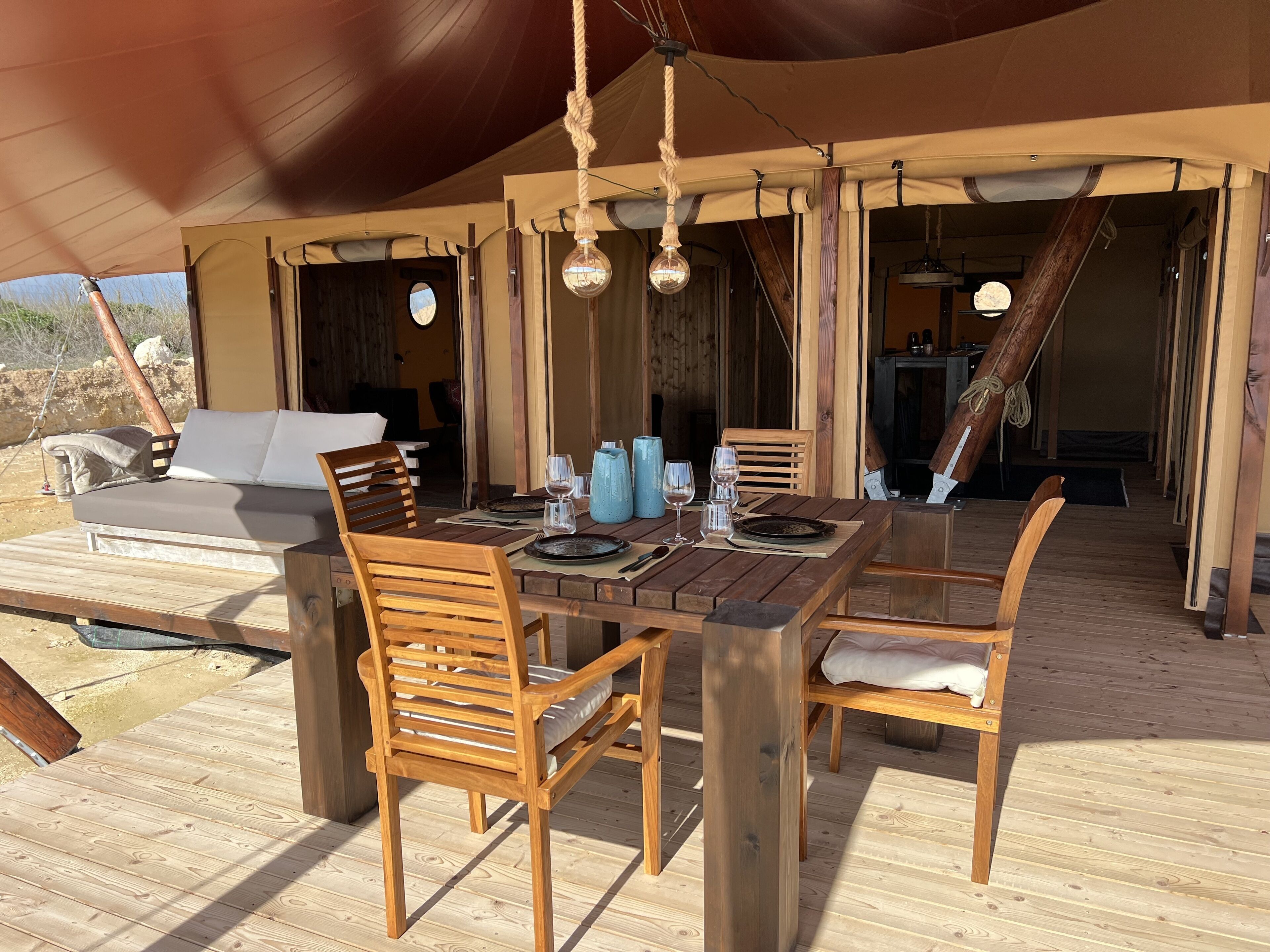 An outdoor dining area with wooden furniture and a tent overhead.