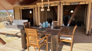 Un espace extérieur aménagé pour les repas, avec des meubles en bois et une tente au-dessus.
