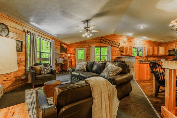 A cozy cabin interior with a living area, a kitchen, and a dining space.