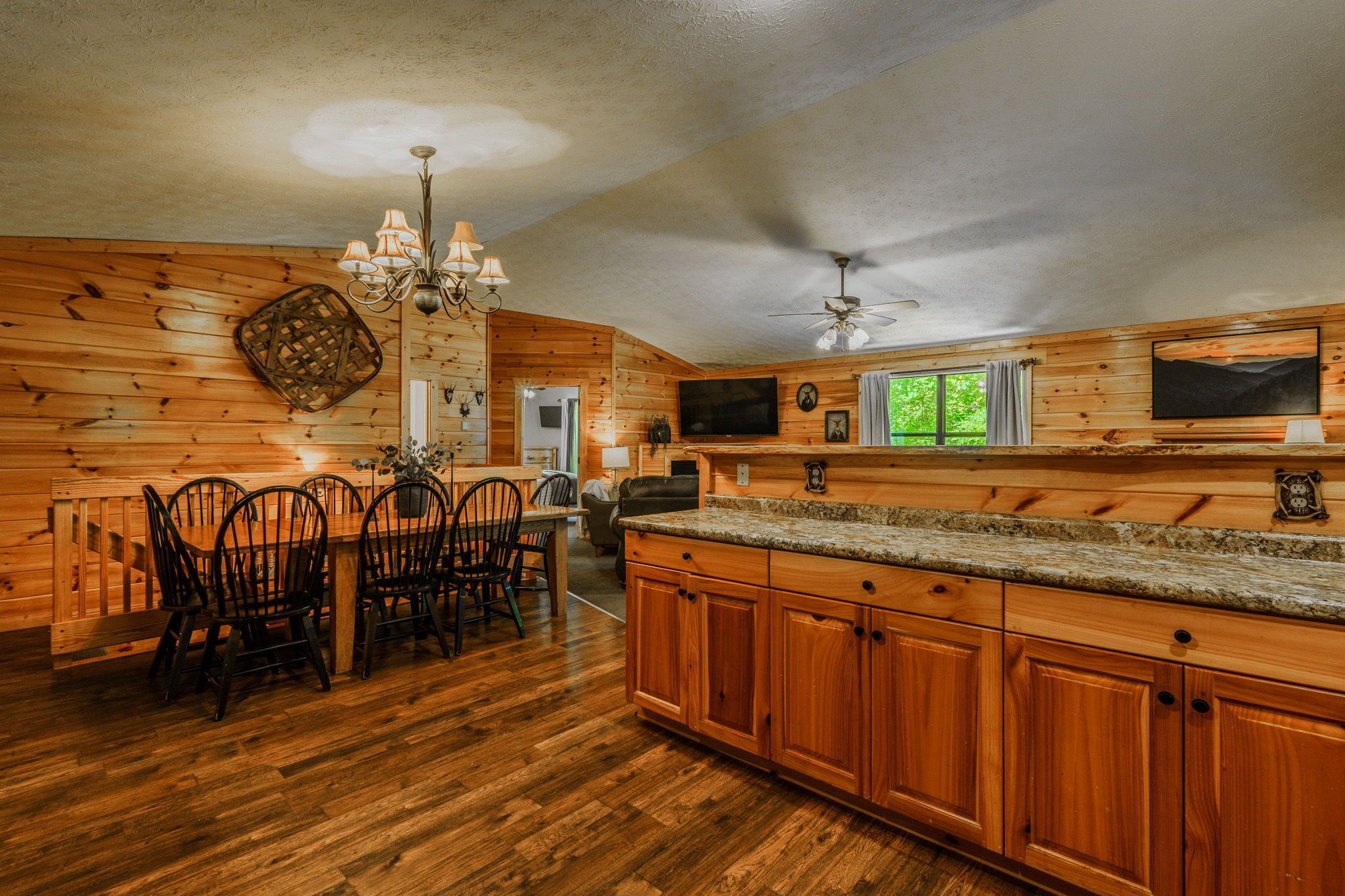 A wooden interior with a dining area, kitchen, and a ceiling fan.