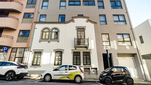 A multi-story building with a central entrance, a small balcony, and a parking sign. - GuestReady - Secret in Porto (Porto)