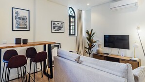 A modern living room with a sofa, a TV, a dining area with chairs, and artwork on the walls. - GuestReady - Secret in Porto (Porto)