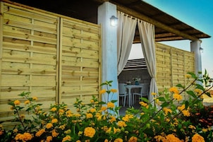 Una estructura de madera con un patio cubierto, que incluye una mesa y sillas bajo un toldo.