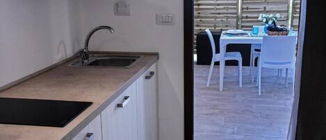 A compact kitchen with a sink, countertop, and cabinets.