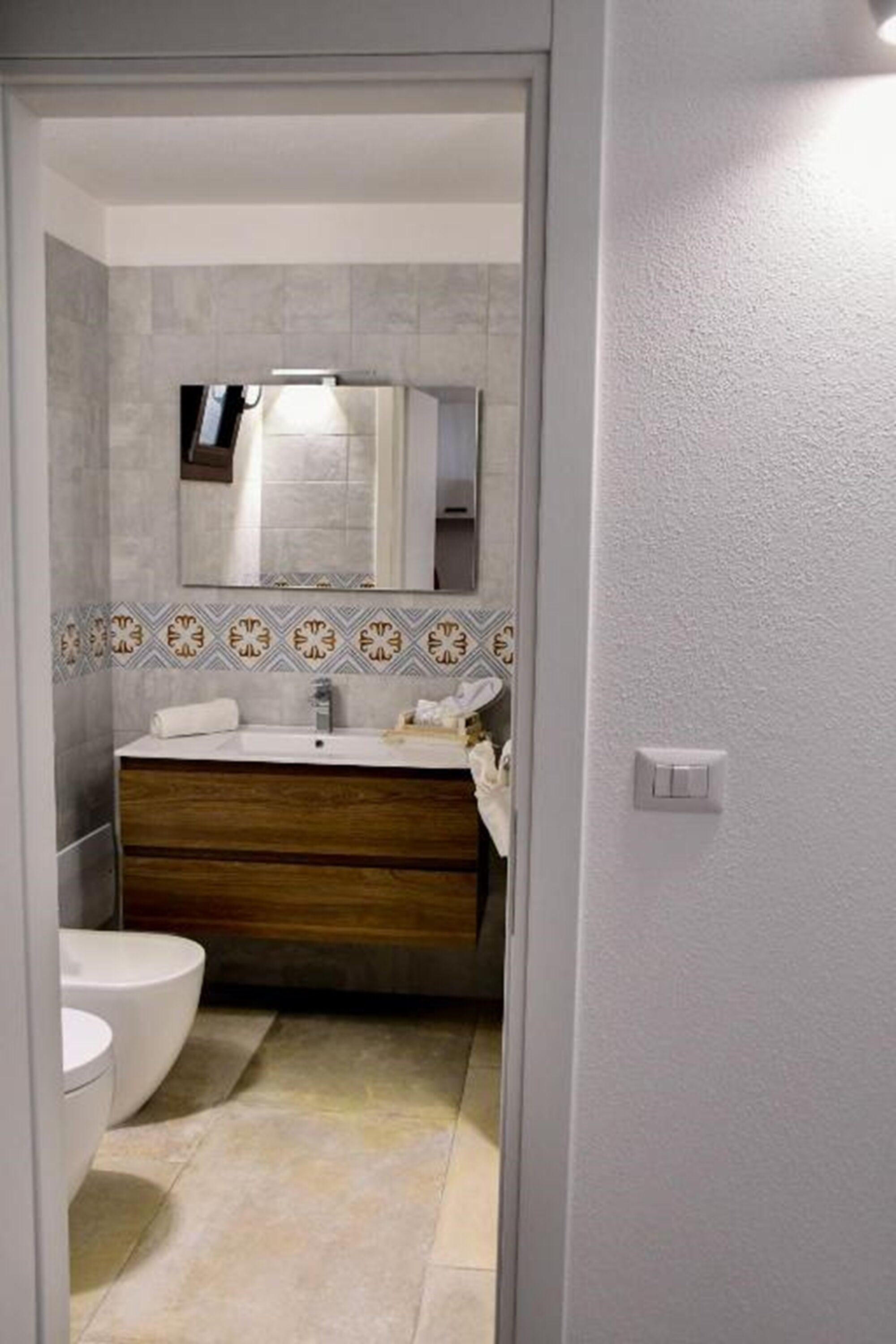 A bathroom with a white sink, wooden vanity, and a toilet.