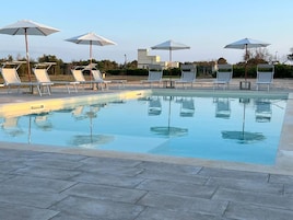 Una piscina con sillones y sombrillas.