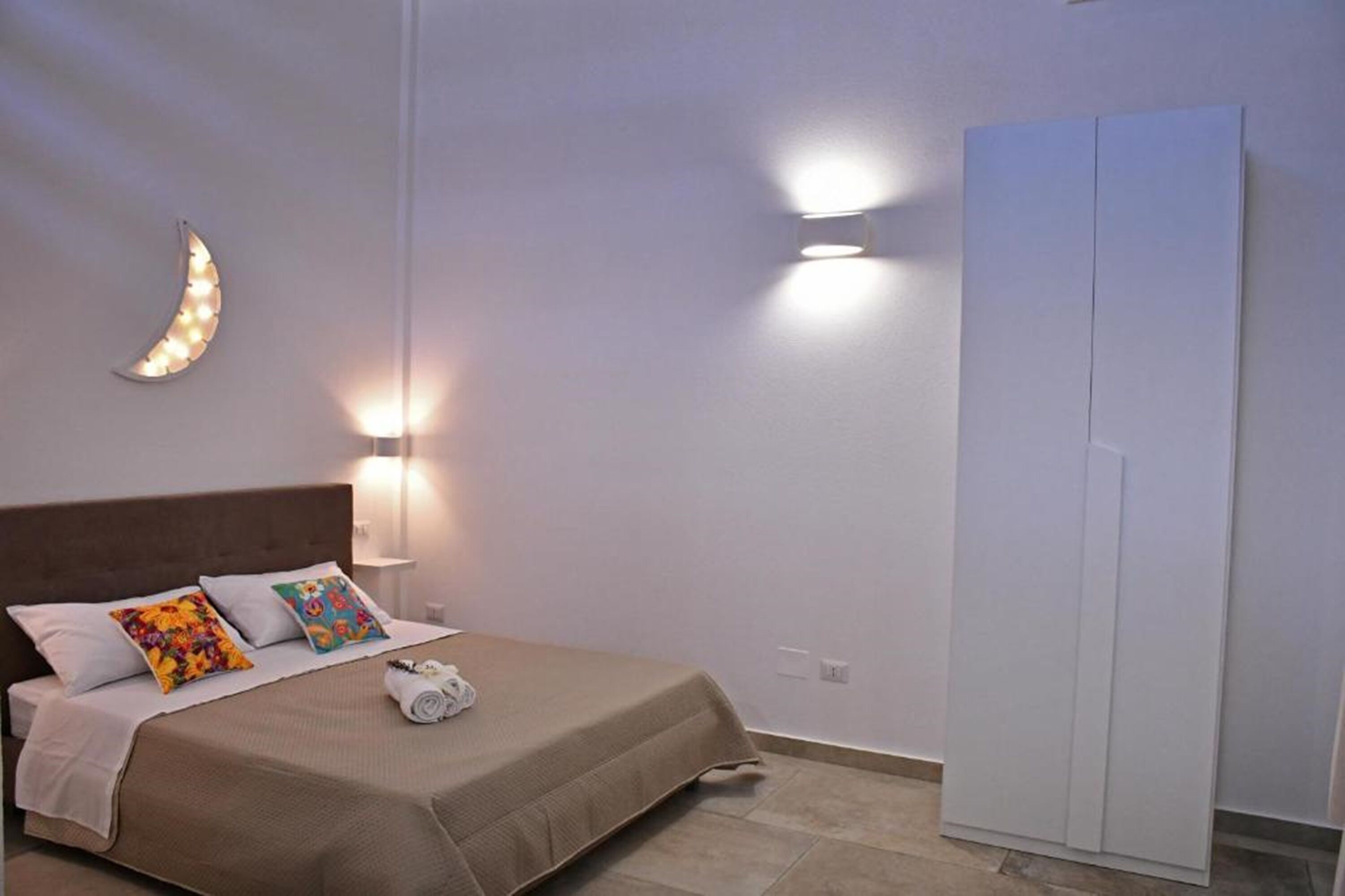 A bedroom with a bed, pillows, a nightstand, and a wardrobe.