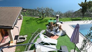 A terrace with a pool, outdoor seating, and a view of a lake.