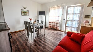 A compact living space with a dining area, a red sofa, and a kitchen area.