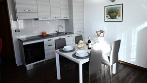 A modern kitchen with white cabinets, a stainless steel sink, and a dining area with a white table and chairs.