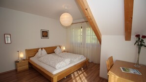 Un dormitorio con cama de madera, mesitas de noche, un escritorio y una lámpara colgante.