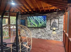A wooden ceiling, a stone wall, a television, and a hammock.
