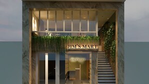 Un edificio moderno con una entrada de doble altura, una escalera y un letrero que dice "JIM'S MART".